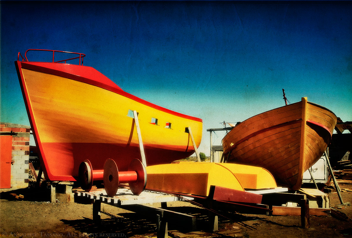 A boat yard near Puerto Madryn, Argentian, filled with wooden boats painted bright colors such as red, yellow, and orange.