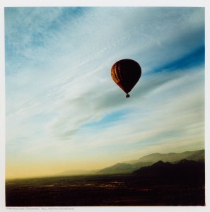 A cross process image of a balloon floating voer the desert valley of Palm Springs, California.
