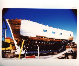 A cross process image shows traditional techniques used to build a wooden fishing boat. It sits braced in a boatyard outside Puerto Madryn, Argentina.
