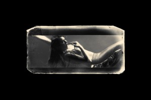 In a Victorian style print, a young mermaid is seen trapped in a tank, biting her long nails and biding her time.